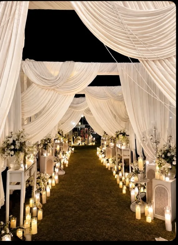 White draped candlelit entrance aisle for an evening event