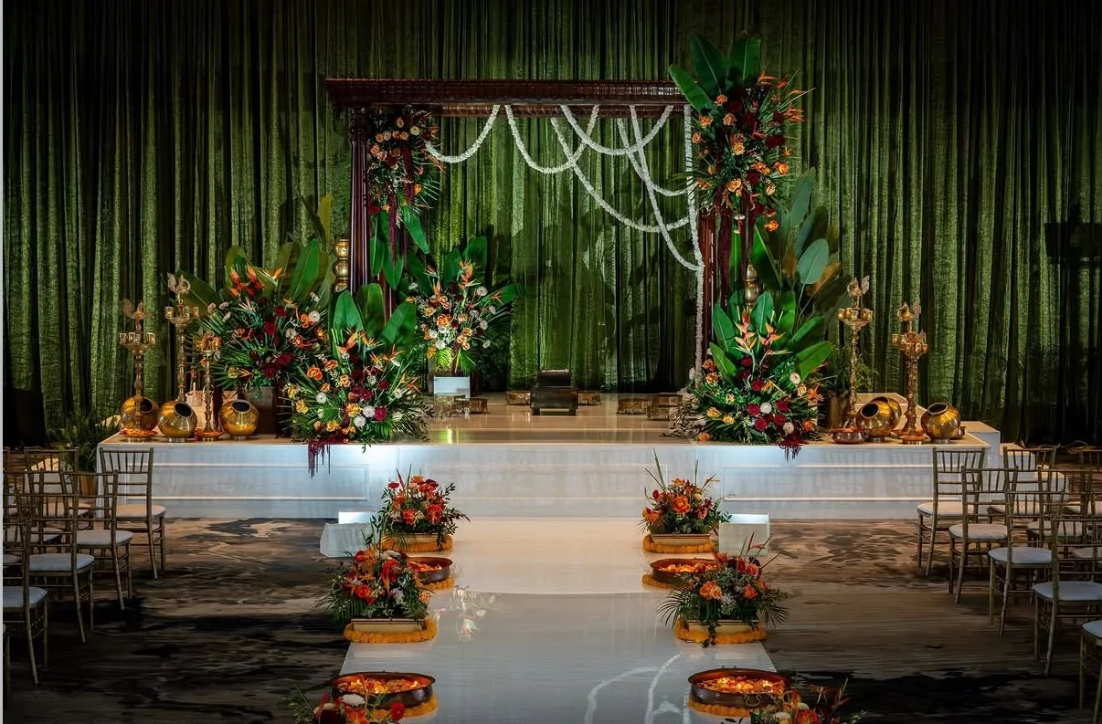 Green floral ceremonial stage with white aisle and flower arrangements